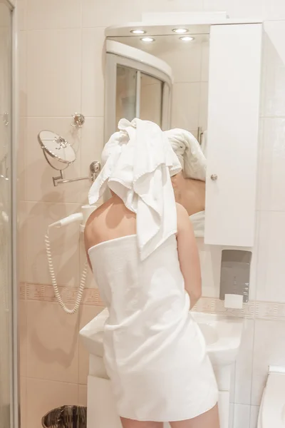 Hübsche Frau cremt ihr Gesicht im Badezimmer ein — Stockfoto