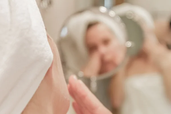 Mulher bonita aplicando creme em seu rosto no banheiro — Fotografia de Stock