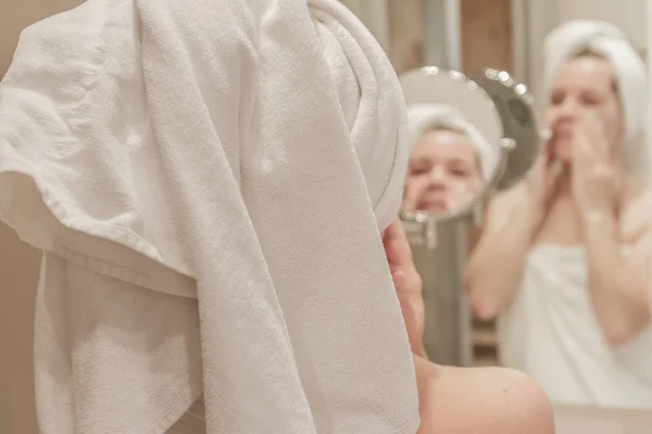 Bella donna che applica la crema sul suo viso in bagno — Foto Stock