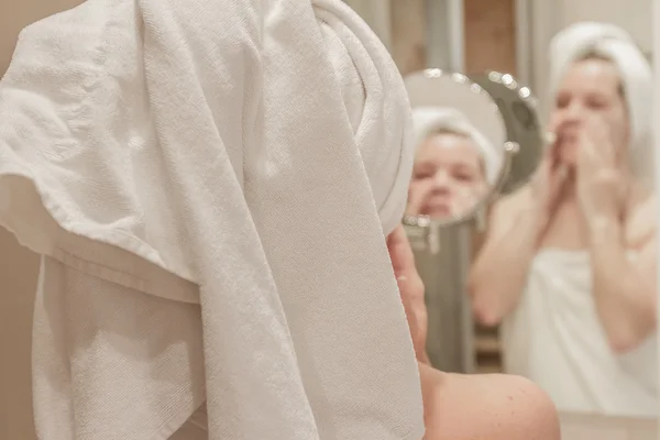 Bella donna che applica la crema sul suo viso in bagno — Foto Stock