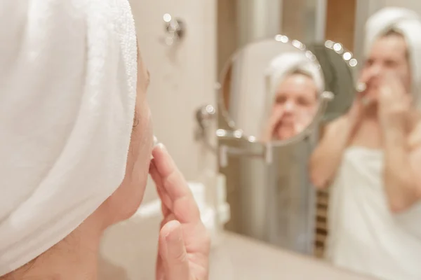 Mulher bonita aplicando creme em seu rosto no banheiro — Fotografia de Stock