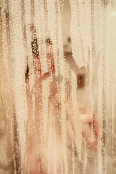 Retrato desfocado de uma mulher tomando banho através da tela do banho — Fotografia de Stock