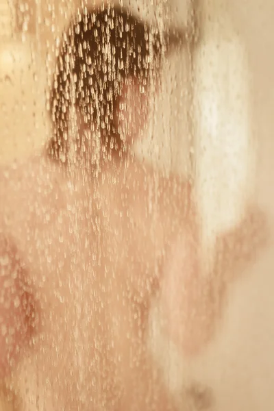 Retrato desfocado de uma mulher tomando banho através da tela do banho — Fotografia de Stock