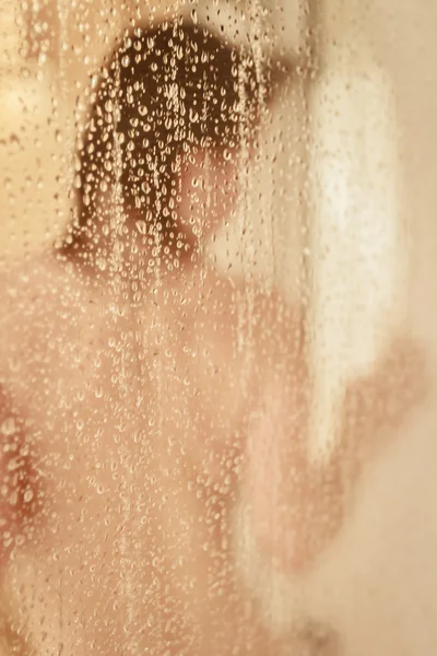 Retrato desfocado de uma mulher tomando banho através da tela do banho — Fotografia de Stock