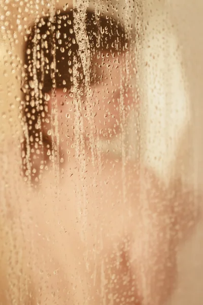 Ritratto sfocato di una donna che fa la doccia attraverso lo schermo del bagno — Foto Stock