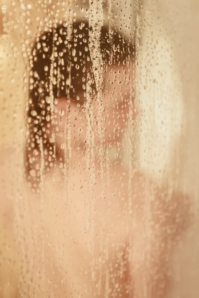 Retrato desfocado de uma mulher tomando banho através da tela do banho — Fotografia de Stock