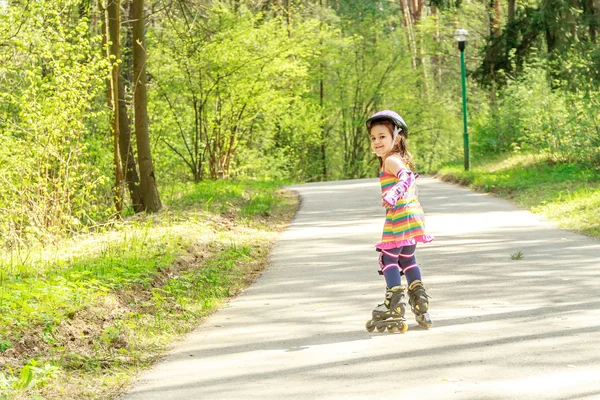 Niña en equipo de protección y rodillos en el parque, al aire libre —  Fotos de Stock