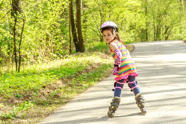 Niña en equipo de protección y rodillos en el parque, al aire libre —  Fotos de Stock