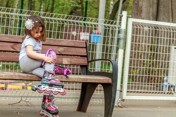 Niña en equipo de protección y rodillos en el parque, al aire libre — Foto de Stock