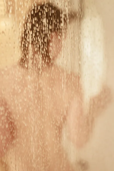 Unfocused portrait of a woman showering through the bath screen — Stock Photo, Image