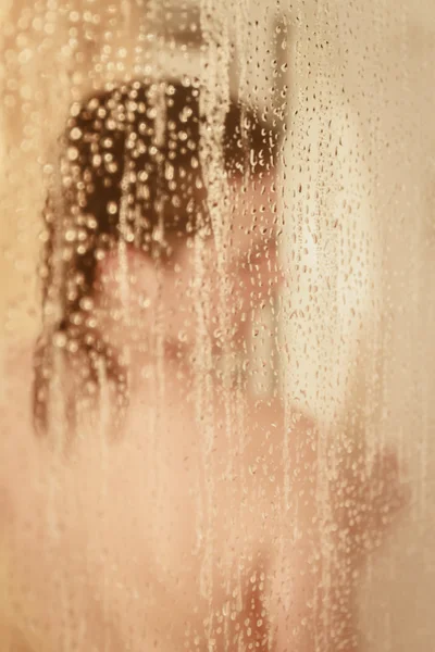 Unfocused portrait of a woman showering through the bath screen — Stock Photo, Image