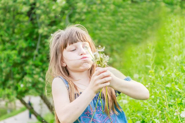 Krásné dítě dívka s pampelišky květiny v jarním parku. Veselé — Stock fotografie