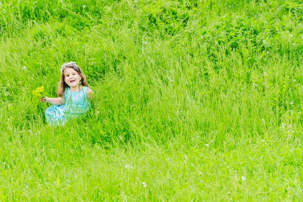 Schöne Kind Mädchen mit Löwenzahnblüte im Frühlingspark. glücklich — Stockfoto