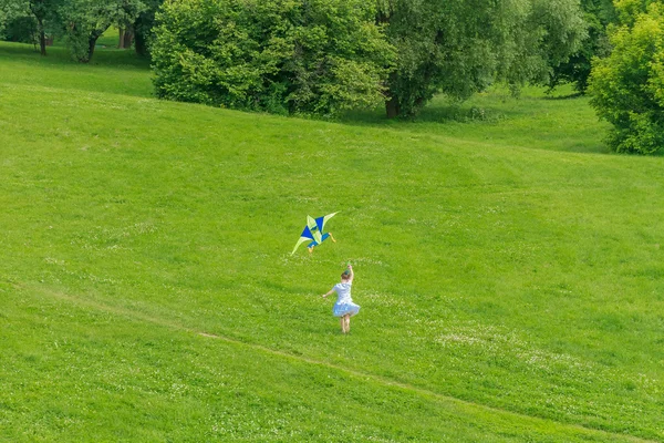 Glada barn flicka som leker med ljusa kite i park. sommaren — Stockfoto