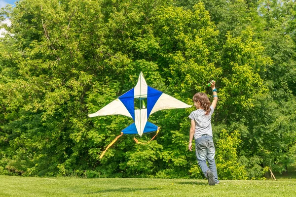 Jovem menino feliz brincando com papagaio brilhante no parque. Verão h — Fotografia de Stock