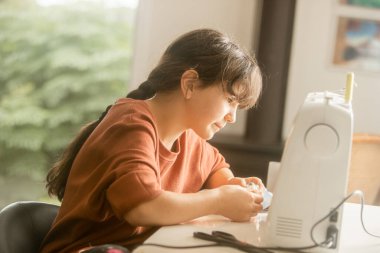 Dikiş makinesiyle evde dikiş diken kız çocuğu