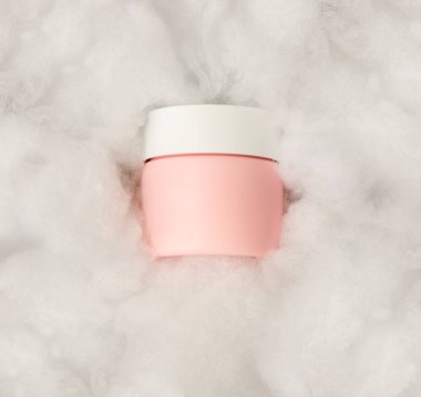 Beyaza izole edilmiş bir güzellik kreminin pembe plastik kavanozu.
