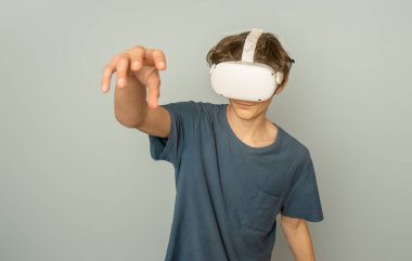 Gri arka plan, dijital teknoloji konsepti ve yenilikçi teknolojiler üzerinde sanal gerçeklik oynayan genç çocuk