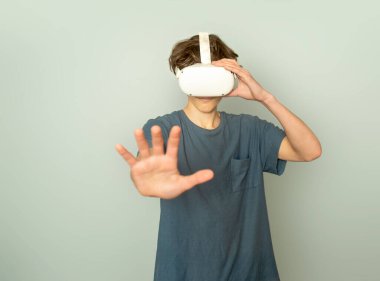 Gri arka plan, dijital teknoloji konsepti ve yenilikçi teknolojiler üzerinde sanal gerçeklik oynayan genç çocuk