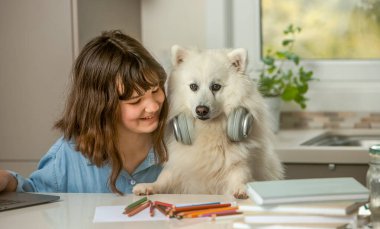 Çevrimiçi ödev yapan genç bir kızın portresi, evcil köpeğiyle evde eğitim, uzaktan öğrenme.