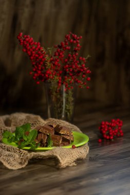 Tatlı olarak sunulan sütlü çikolata. Arka planda kırmızı böğürtlen, Noel yemeği, yılbaşı arifesi.