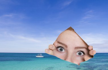 young woman looking though hole at tropical sea - concept shot clipart