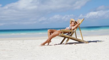 tropikal deniz arka plan üzerinde yaz şapkalı genç gülümseyen kadın