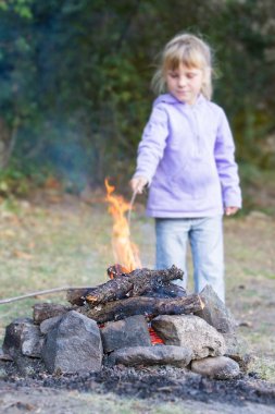 doğal zemin üzerine ateşle oynayan kız çocuk