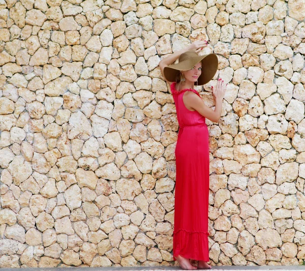 Joven hermosa mujer en sombrero de pie junto a la pared de piedra —  Fotos de Stock