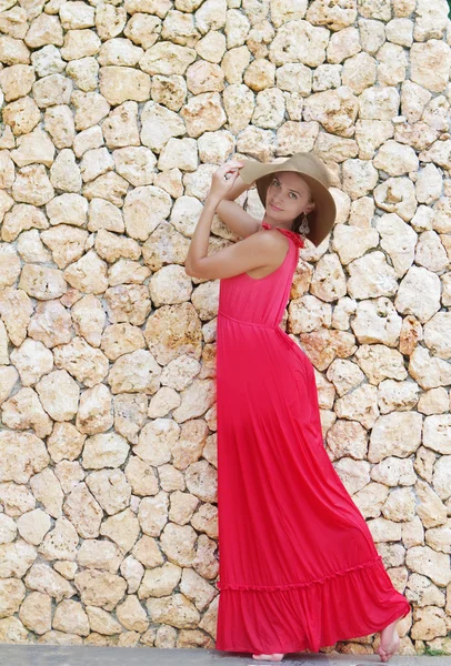 Unga vackra kvinnan i hatt står bredvid stenmur — Stockfoto