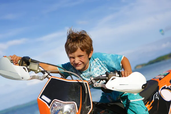 バイクに乗って幸せな笑みを浮かべて少年の屋外のポートレート — ストック写真