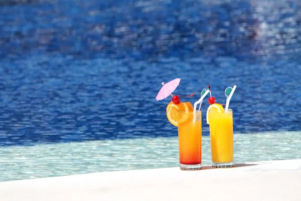 Deux verres de jus de fruits sur fond d'eau bleue — Photo