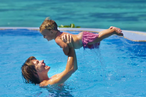 Young happy mother and baby enjoying vacation in swimming pool o — Stock Photo, Image