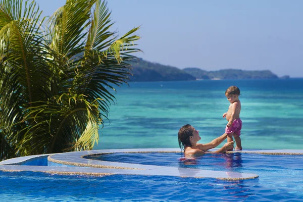 Giovane madre felice e bambino godendo la vacanza in piscina o — Foto Stock