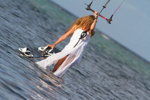 Jovem bela mulher no vestido de noiva kitesurfing na água de volta — Fotografia de Stock