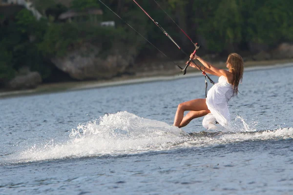 Mladá krásná žena ve svatebních šatech kitesurfing na vodě zpět — Stock fotografie