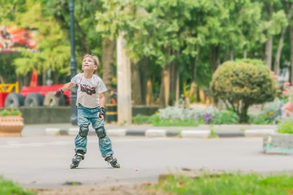 Gelukkige jongen faving plezier op roller scates op natuurlijke pagina — Stockfoto