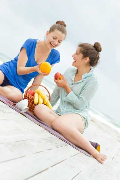 Two young happy women enjoying life during outdoor picnic with f — Stock Photo, Image