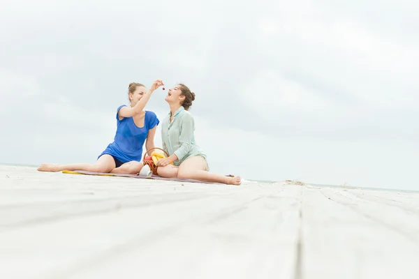 Dos mujeres felices jóvenes disfrutando de la vida durante el picnic al aire libre con f —  Fotos de Stock