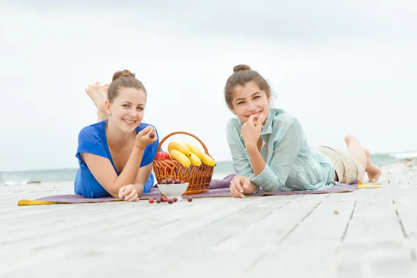 Dos mujeres felices jóvenes disfrutando de la vida durante el picnic al aire libre con f — Foto de Stock