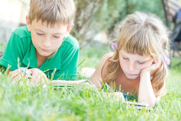 Two young happy kids, children reading books on natural backgrou — Stock Photo, Image