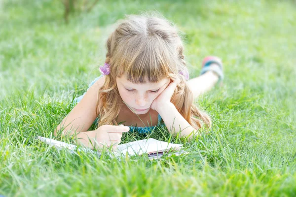 Niña leyendo libro al aire libre sobre fondo natural —  Fotos de Stock