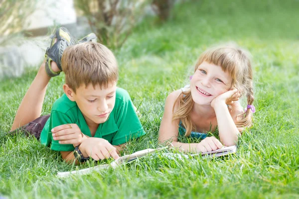 Two young happy kids, children reading books on natural backgrou — Stock Photo, Image