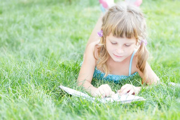 Niña leyendo libro al aire libre sobre fondo natural — Foto de Stock