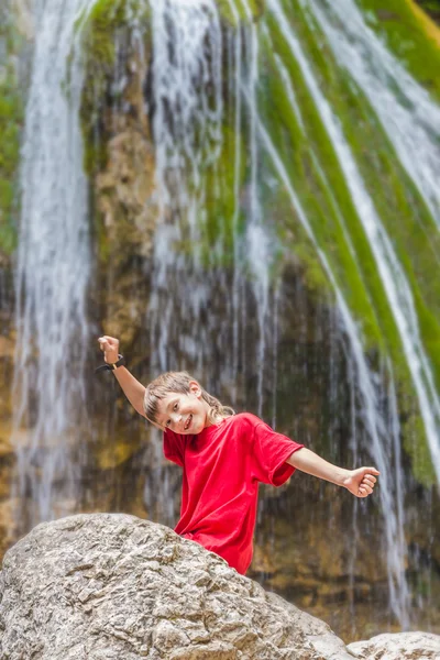 Young happy smiling child boy on waterfall background — Stock Photo, Image