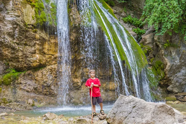 Young happy smiling child boy on waterfall background — Stock Photo, Image