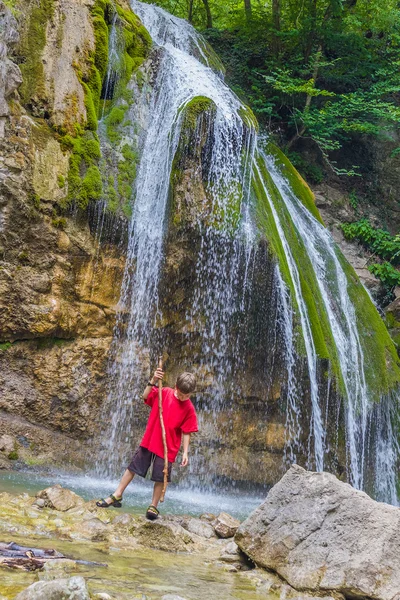 Young happy smiling child boy on waterfall background — Stock Photo, Image