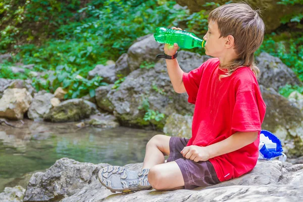 Jovem feliz sorridente criança boydrinking água na floresta rio de volta — Fotografia de Stock