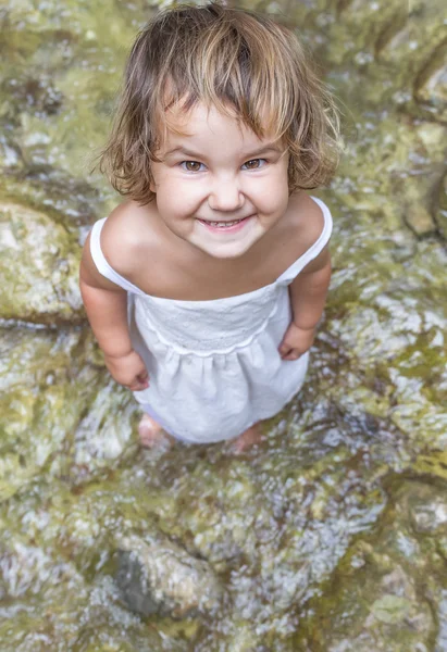 Cute smiling toddler child girl on waterfall background — Stock Photo, Image