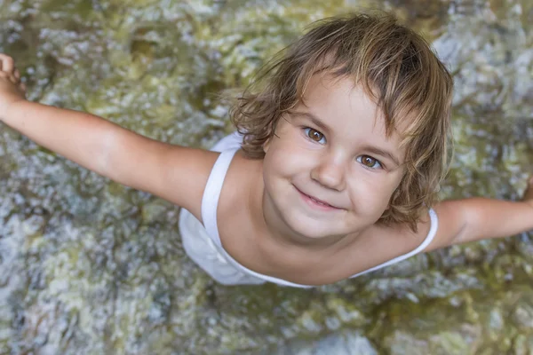 Cute smiling toddler child girl on waterfall background — Stock Photo, Image